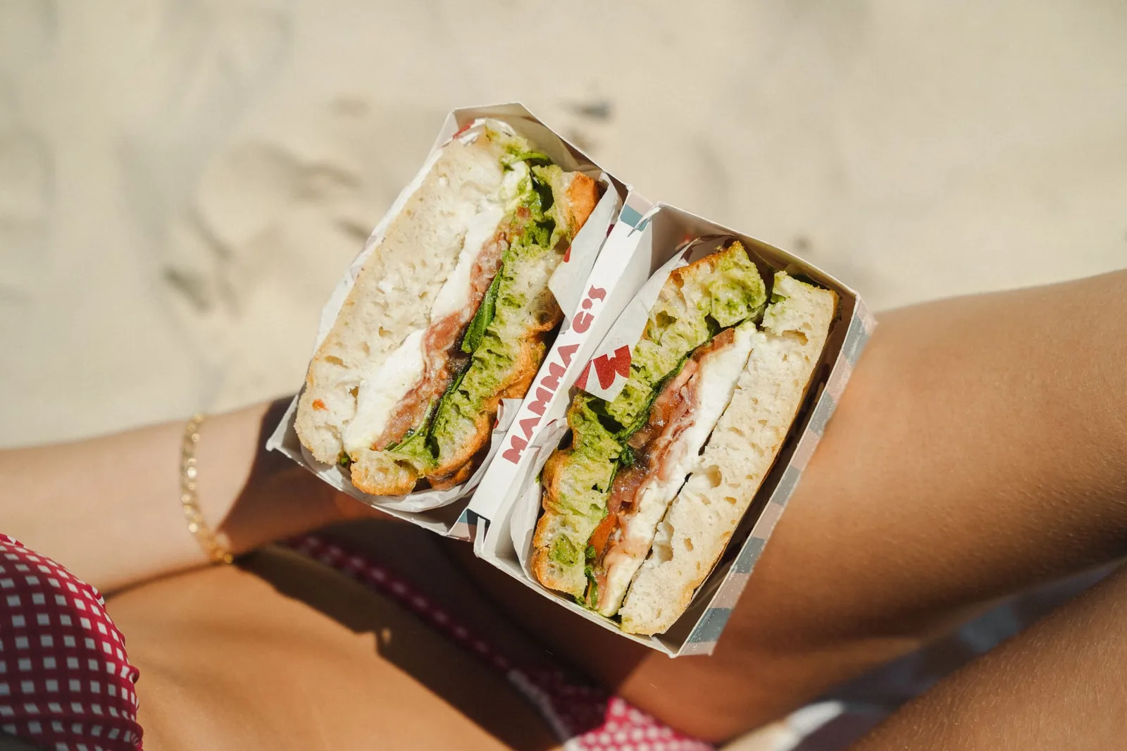 Striped Mamma G's boxes of focaccia sandwiches open on the sand