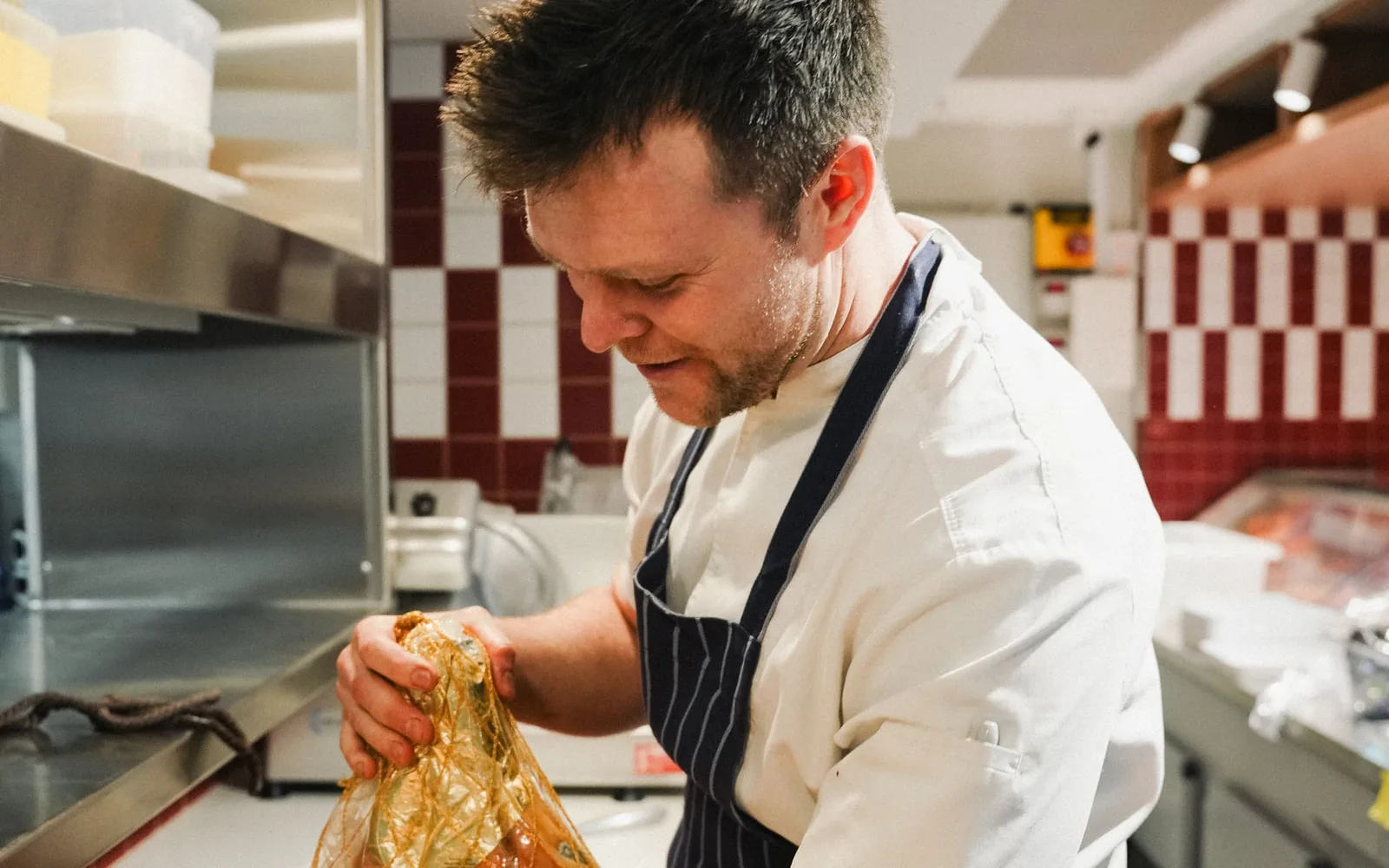 A chef unwrapping a whole leg of Carpegna prosciutto