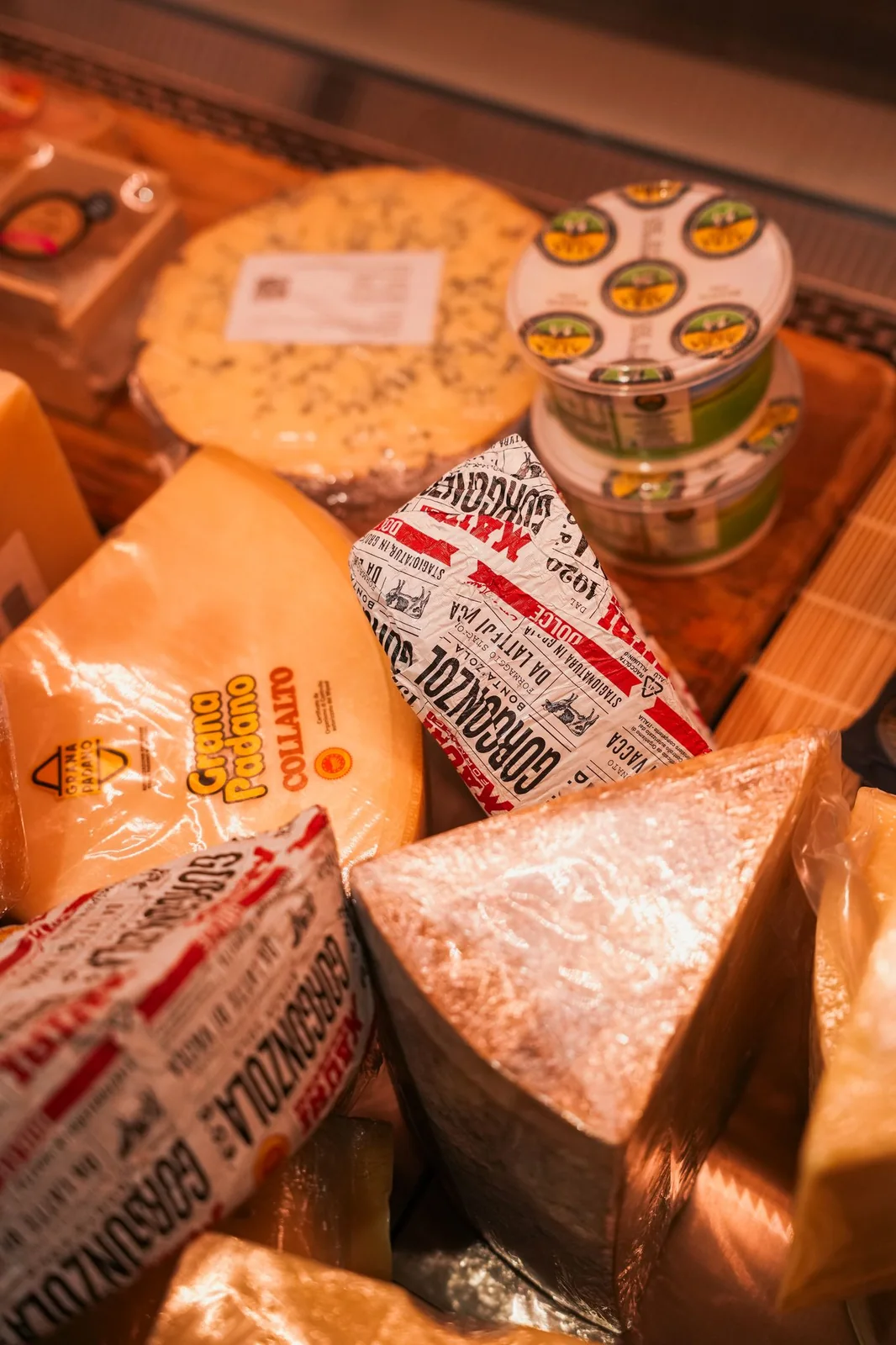 Wheels and wedges of cheese and packets of salumi in the Mamma G's deli display case