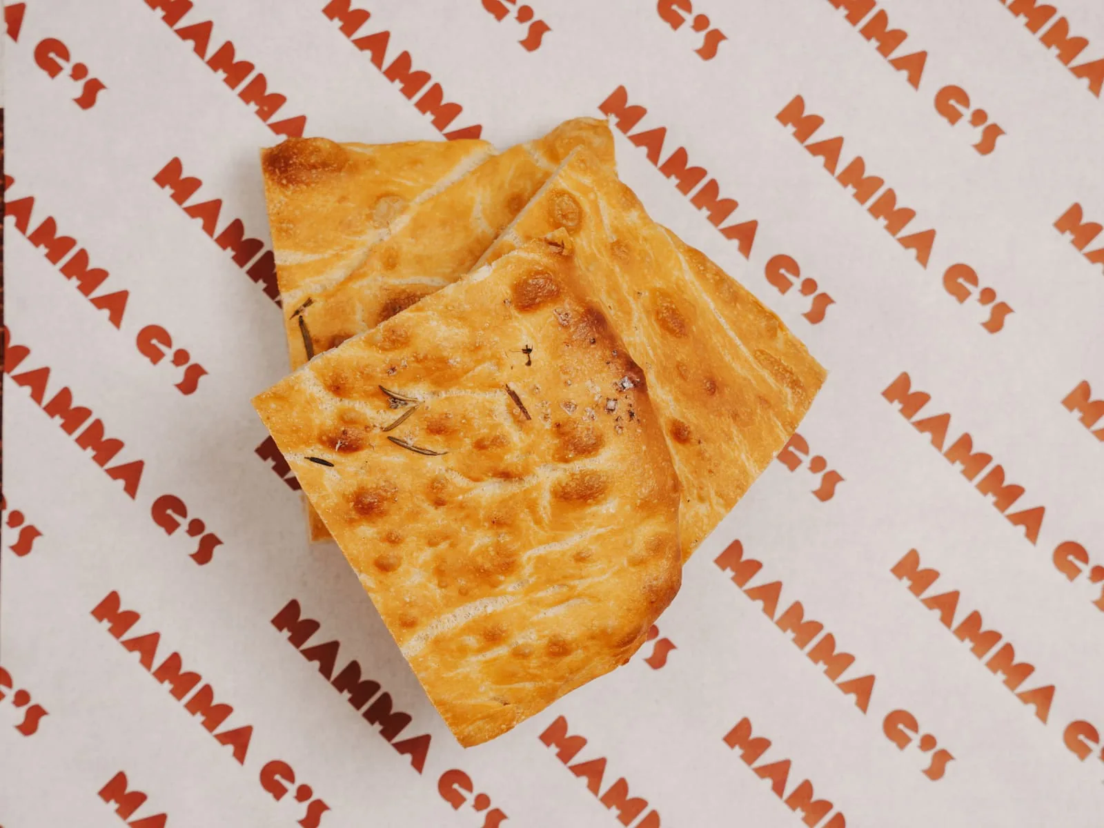 Two pieces of fresh focaccia on Mamma G's branded paper
