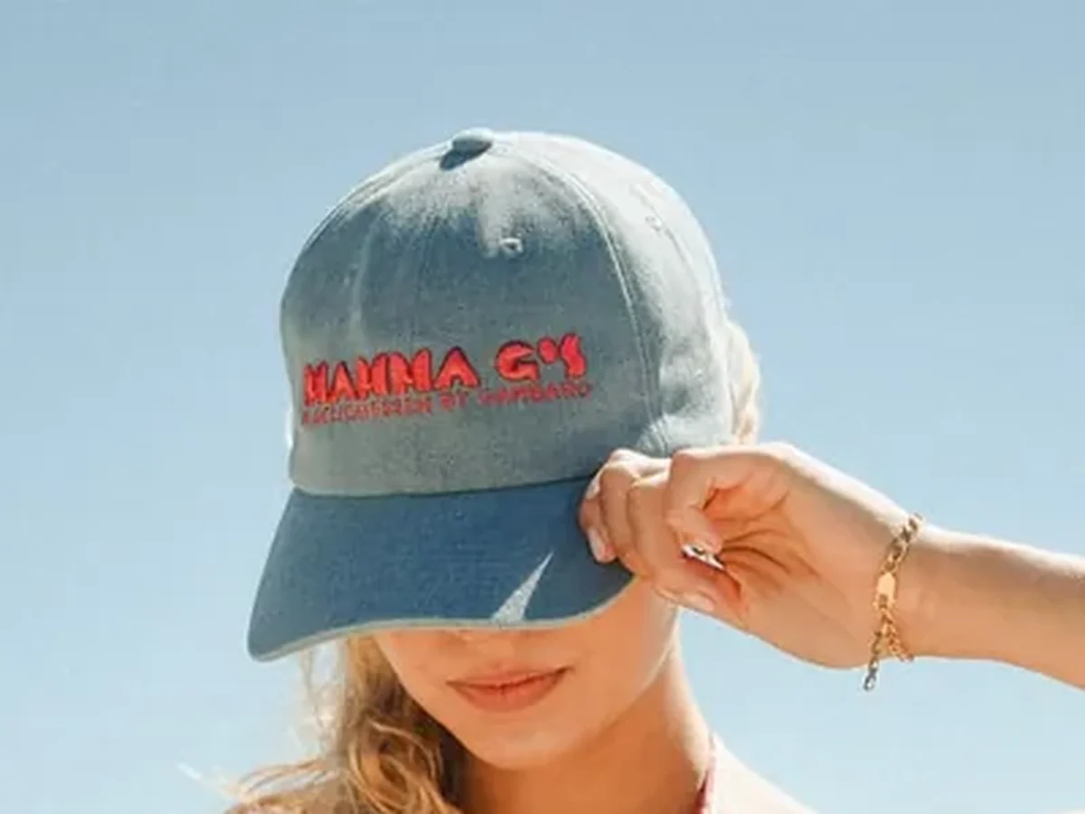 The Mamma G's washed denim cap, wordmark embroidered in red, against a clear sky