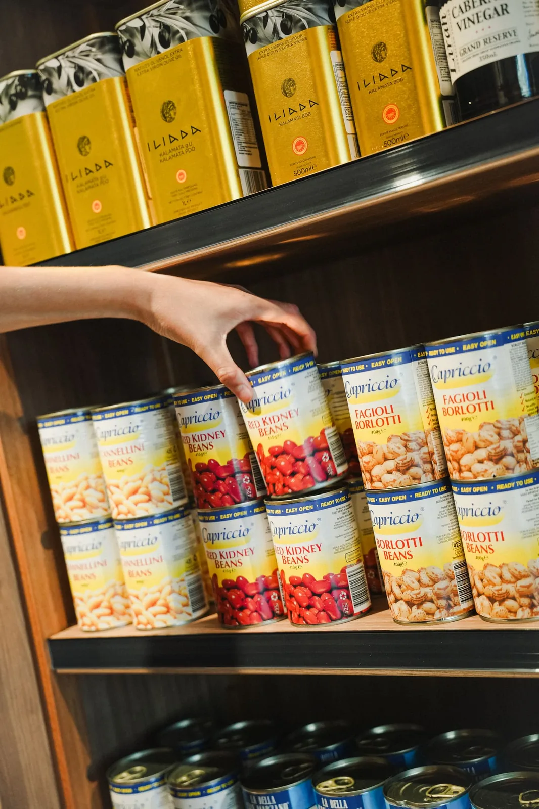 Reaching for a tin from a shelf of Italian tinned goods
