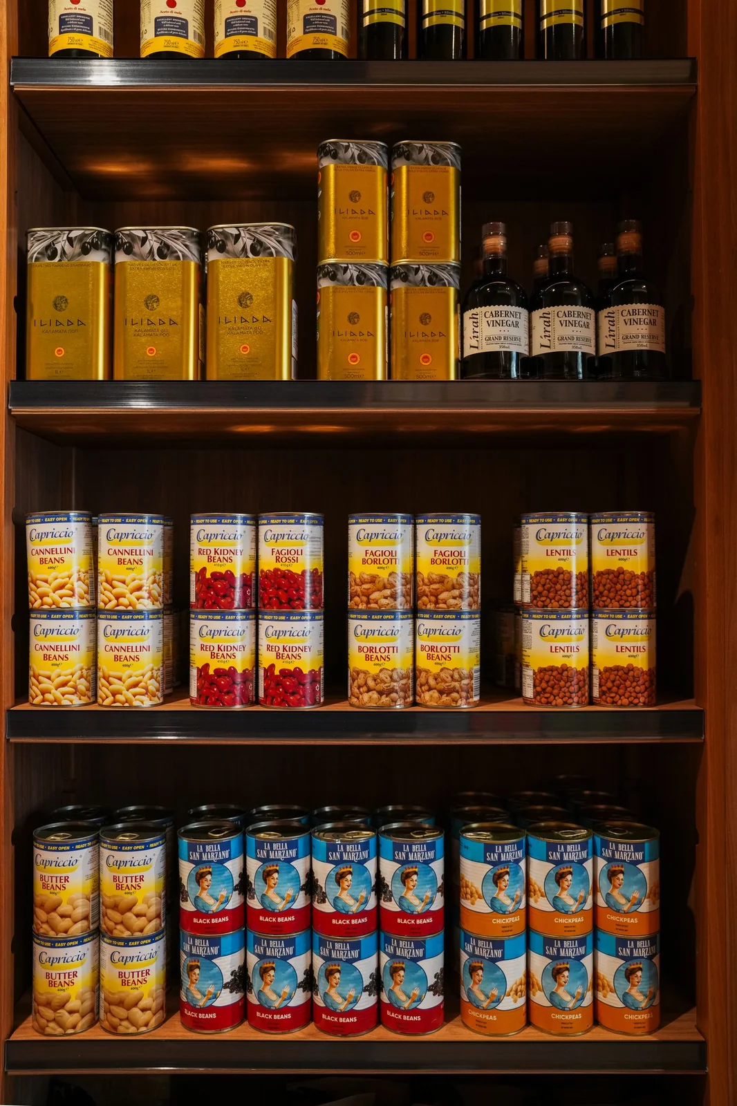 Timber pantry shelves stacked with olive oils, tinned tomatoes and Italian preserves